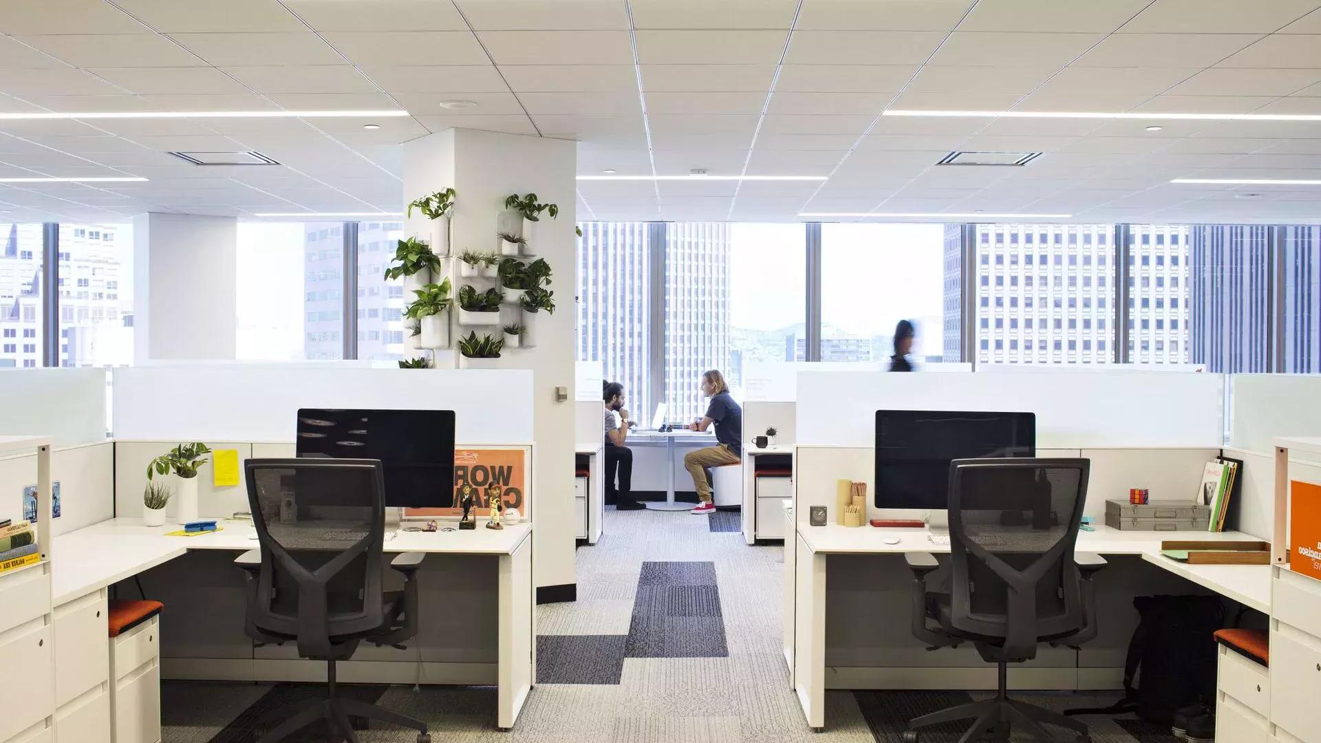 贝博体彩app一幢办公楼的室内场景, 桌子在前面，两个人在大窗户前的桌子上工作.